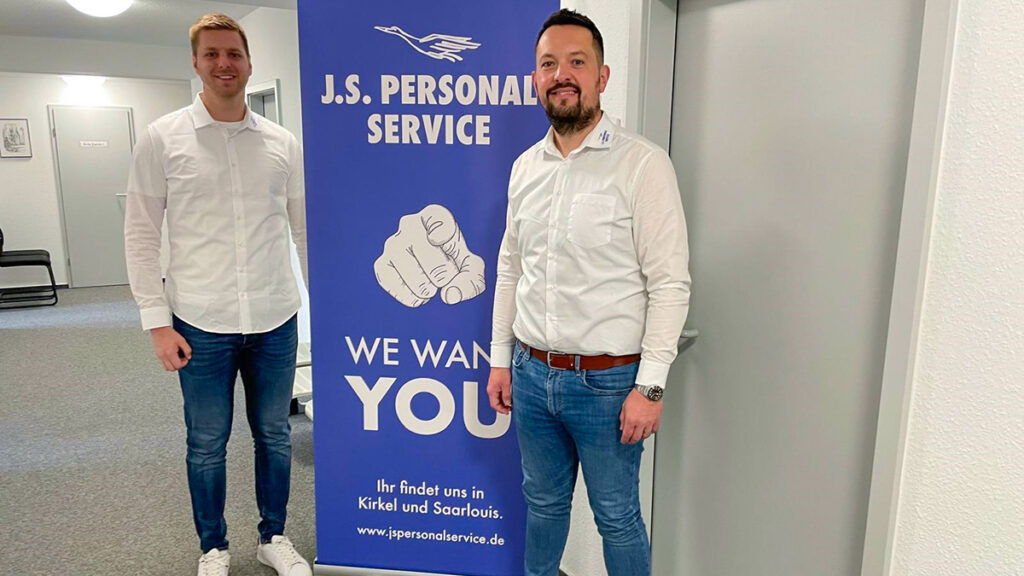 Mitarbeiter vor Plakat für Jobmesse Merzig